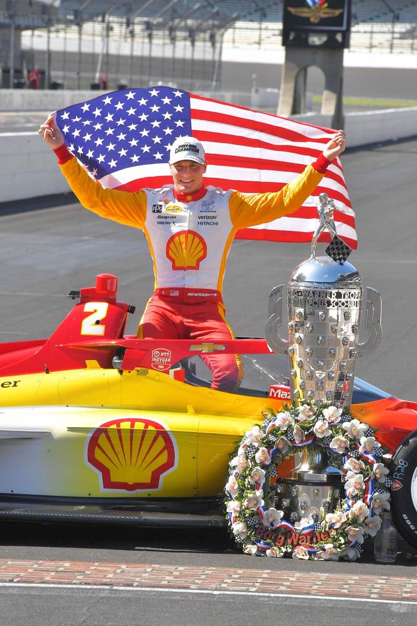 Man holds American flag behind back while sitting in race car