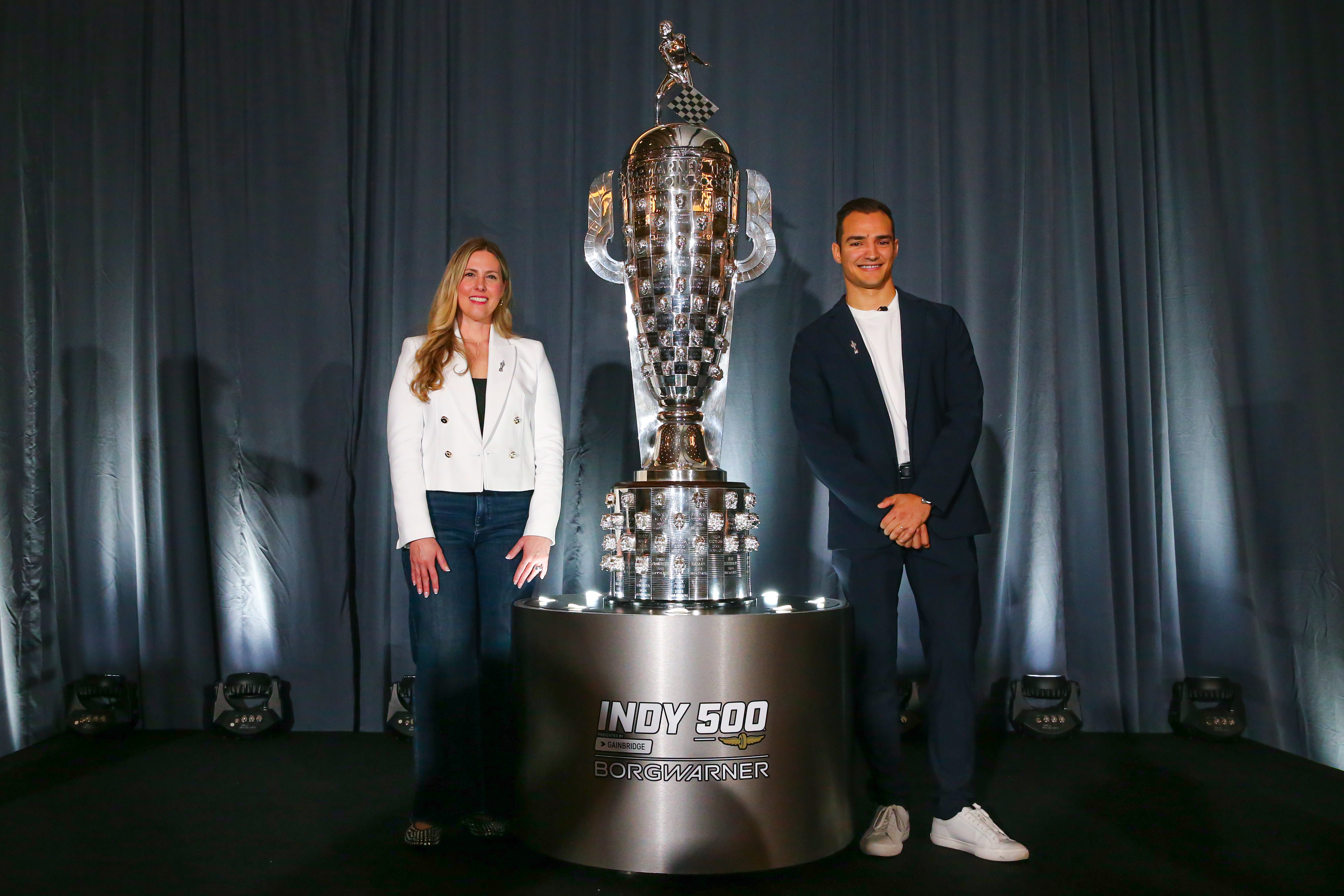 Man and woman pose next to large silver trophy