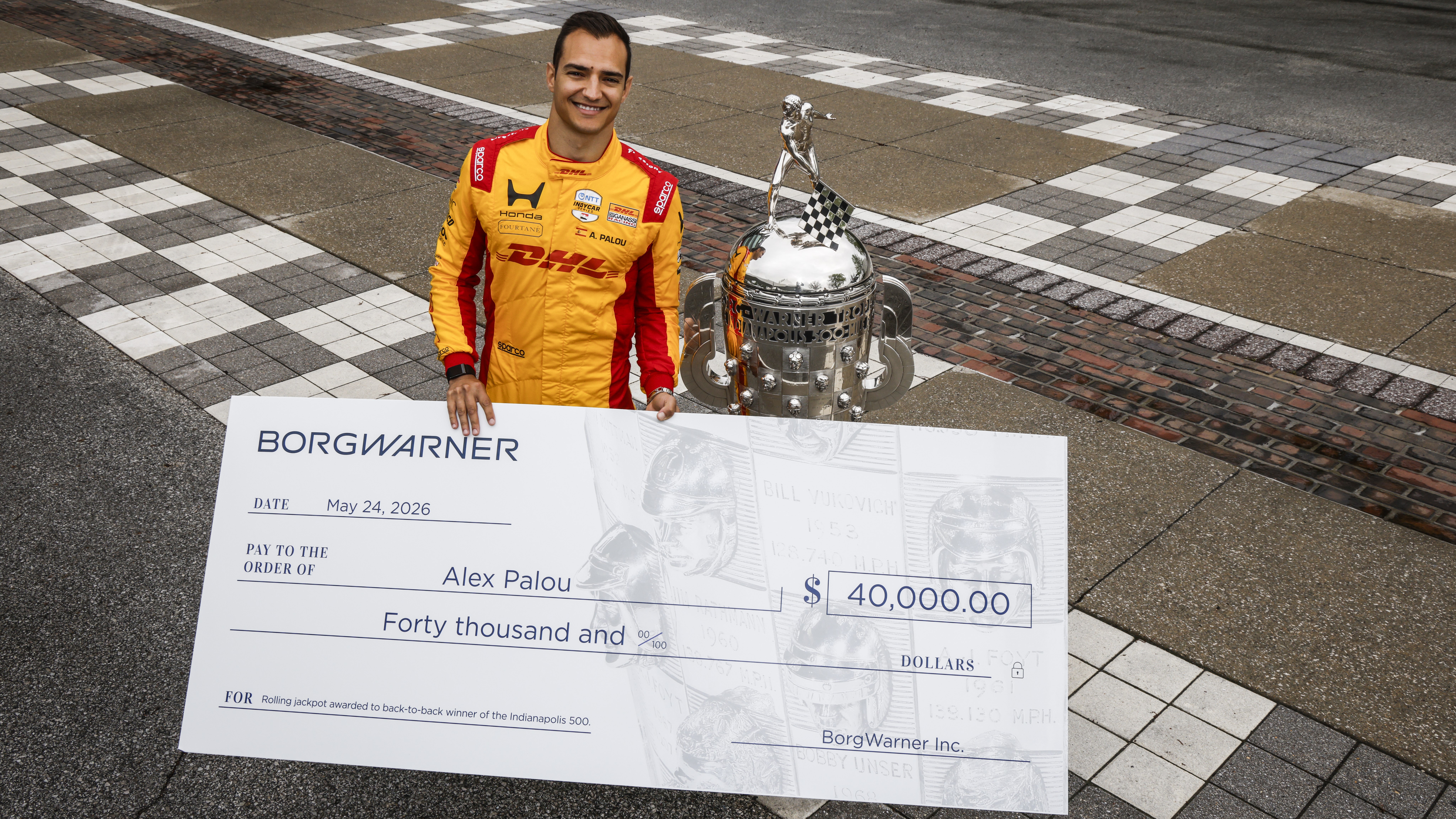 Alex Palou smiles with the Borg-Warner Trophy and oversized check for $40,000