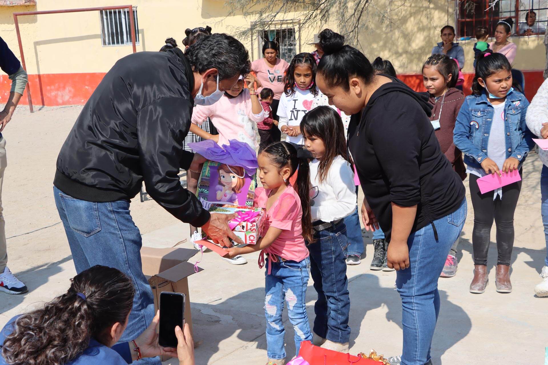 a group of people standing outside giving presents to children